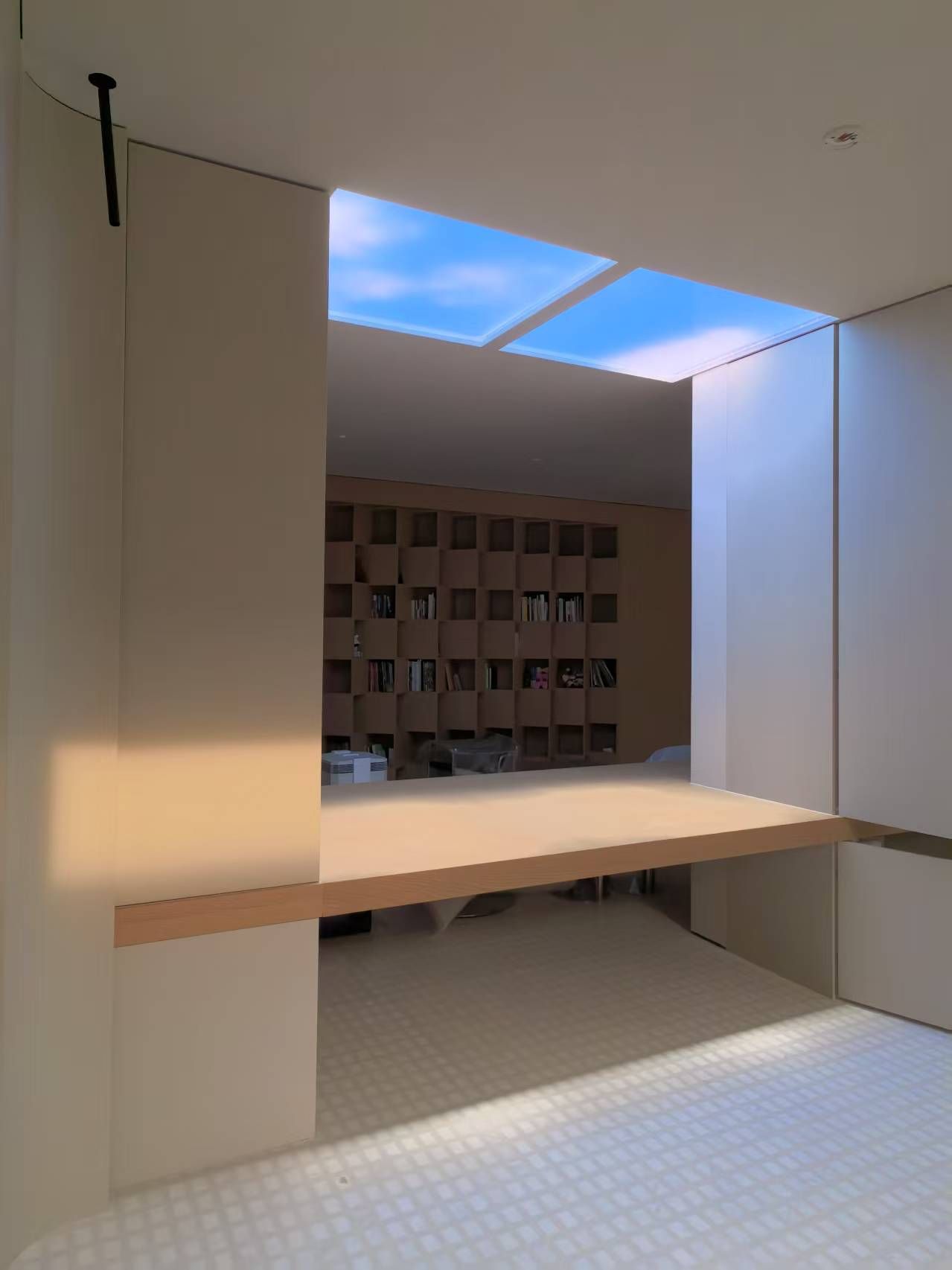 Dynamic sky artificial skylight above a built-in daybed and bookshelf nook
