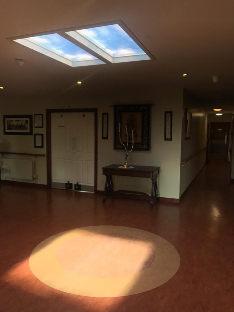 Pair of 1200x600mm artificial skylights above a retirement village entry foyer, set to warm 2500K lighting to create a comfortable, welcoming first impression for residents and visitors.