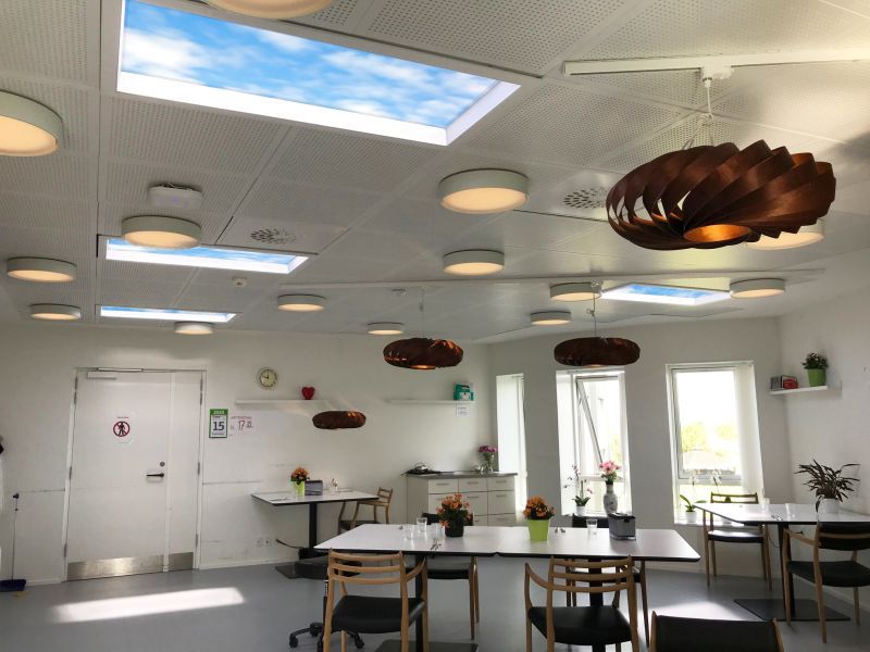 Multiple 1200x600mm static cloud skylights across a nursing home dining/common room ceiling, combined with pendant lighting to create a bright, sociable atmosphere during meals and help residents maintain a healthy daily routine.