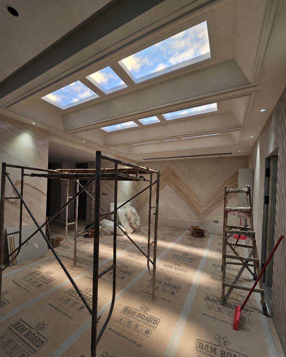 Static cloud skylight above an internal dressing/wardrobe corridor, giving a windowless space a natural daylight glow.