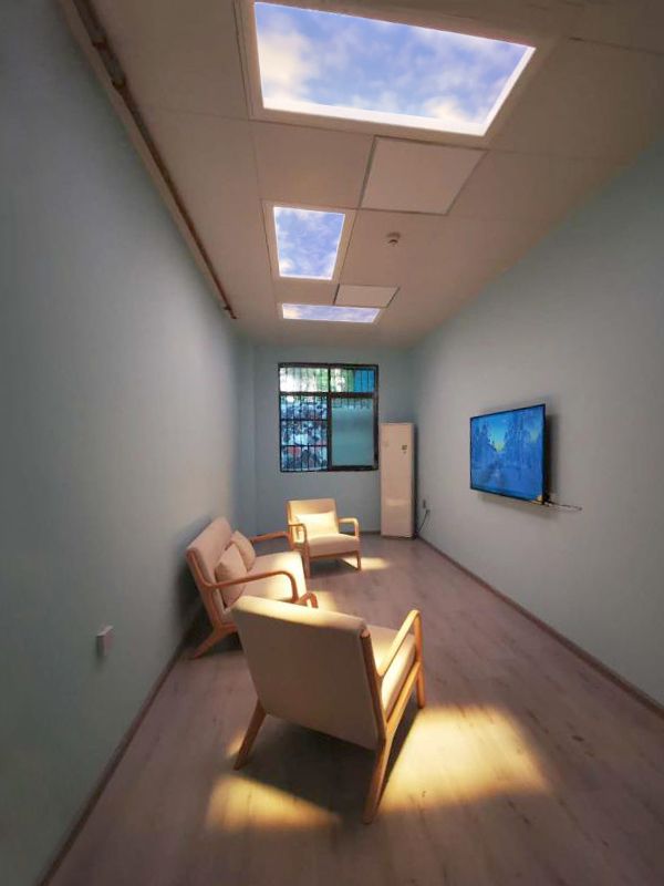 Three static cloud skylights above a psychiatry department therapy room, furnished with lounge chairs to give patients a calm, naturally lit space for sessions.