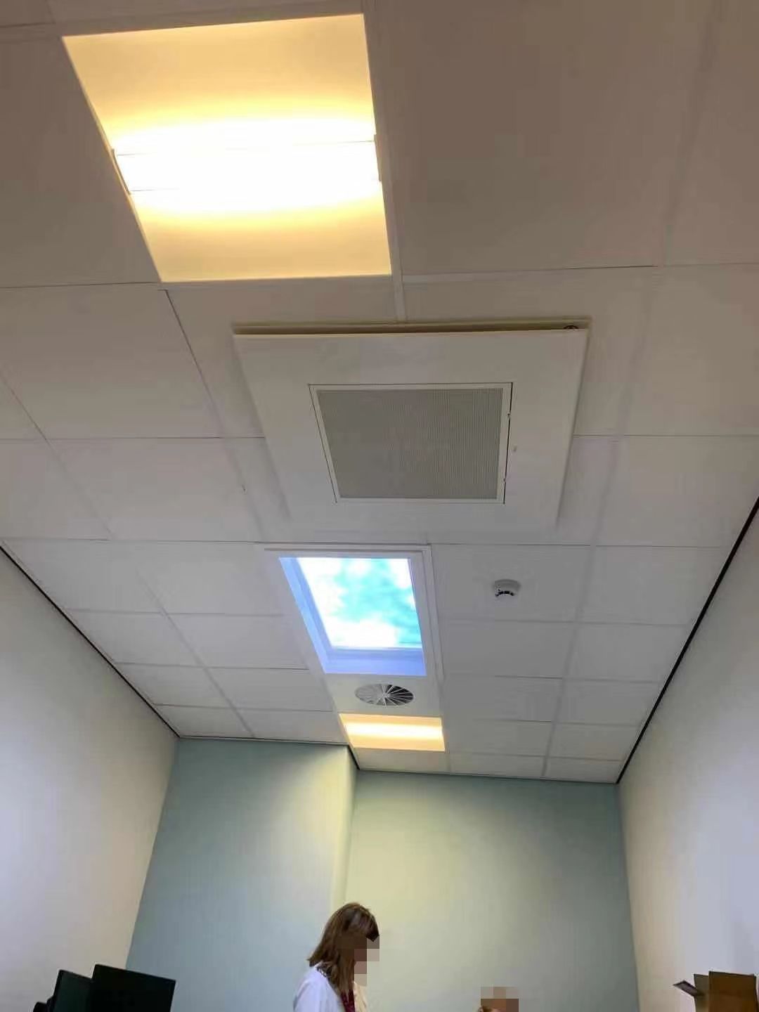 Close-up ceiling view of the same treatment room, showing the skylight installed alongside a downlight and air vent.