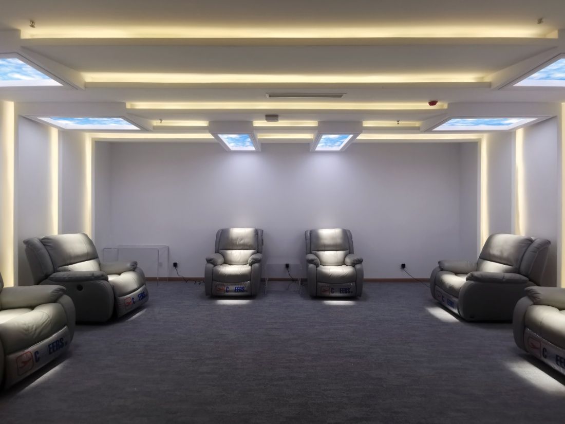 Row of six static cloud skylights above a hospital light-therapy recliner room, delivering a consistent daily bright-light dose to patients during treatment sessions.