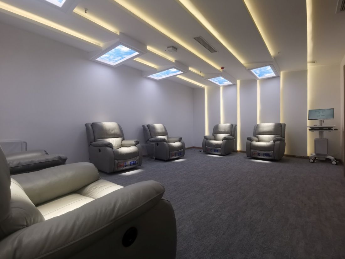 Second angle of the same light-therapy recliner room, showing the full row of skylights above the reclining chairs.