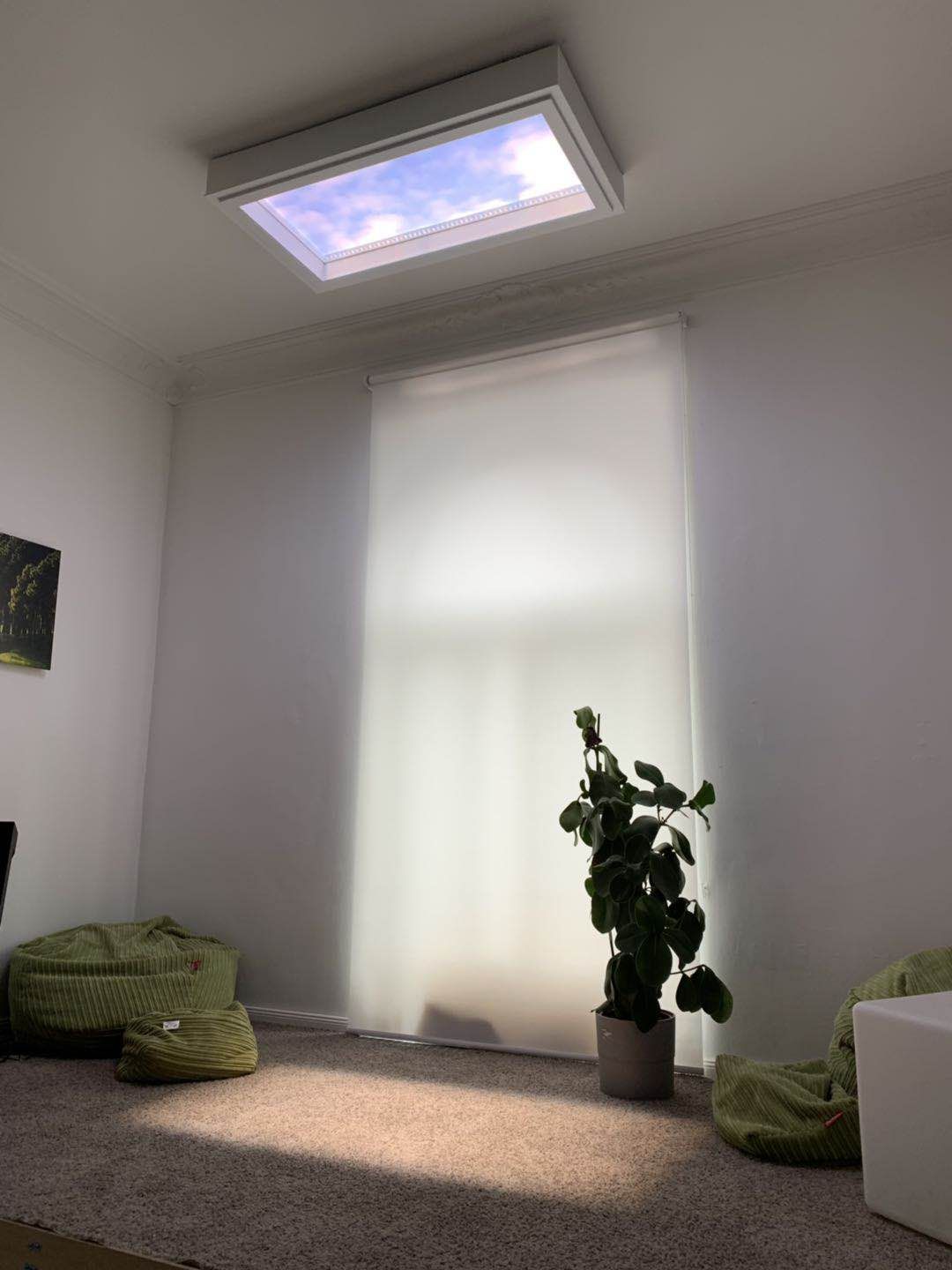 Surface-mounted static cloud skylight above a relaxed lounge nook with floor cushions, bringing daylight into a room set back from any windows.