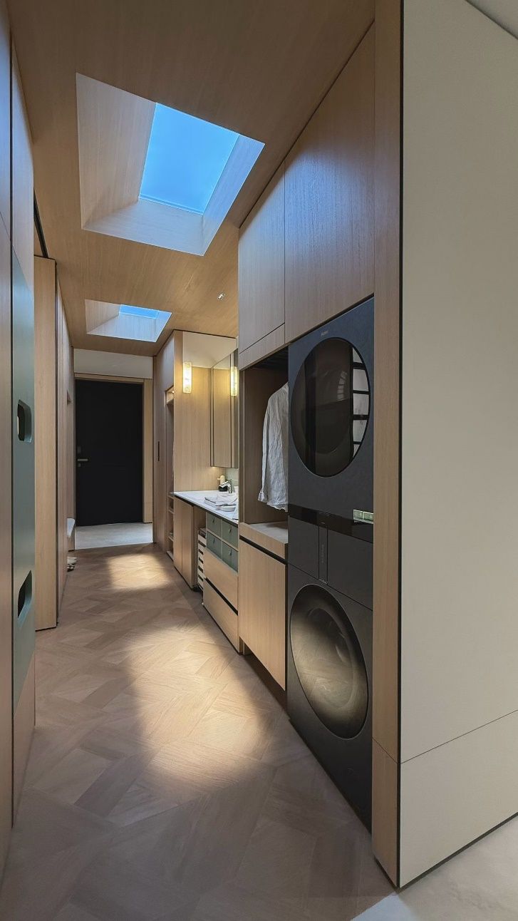 Blue sky skylight above a narrow laundry/utility corridor, bringing daylight into an internal space with no windows and making an everyday chore area feel brighter and less enclosed.