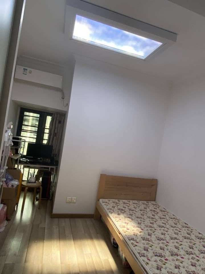 Blue sky skylight above a dining room, bringing natural-feeling light to the table beneath an air-conditioning unit.